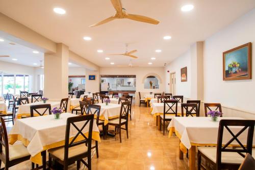 a dining room with white tables and chairs at Hostal Mar y Huerta in Es Cana