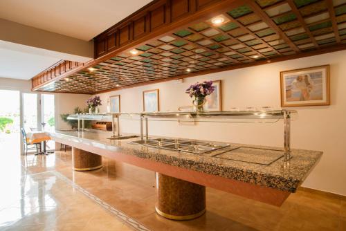 a lobby with a long counter with flowers on it at Hostal Mar y Huerta in Es Cana