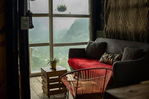 a living room with a red couch and a large window at Cabaña Eco amigable en medio de la montaña. in Pastales