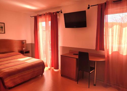 Dormitorio con escritorio, cama y TV en Hôtel de l'Orb, en Bédarieux