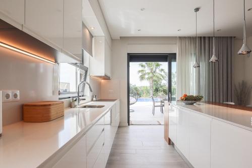 Il comprend une cuisine avec des placards blancs et offre une vue sur une terrasse. dans l'établissement Villa Moroz - BY BEDZY, à Almancil