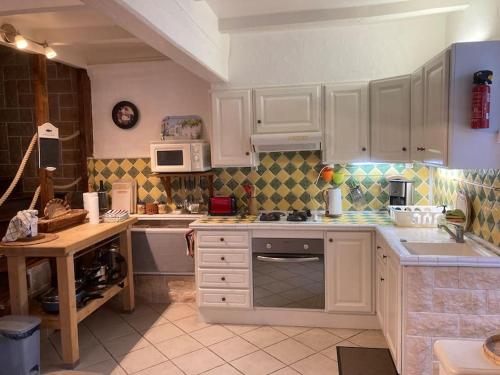 une cuisine avec des armoires blanches et un four à plaques de cuisson dans l'établissement Fisherman`s Cottage, à Mortagne-sur-Gironde
