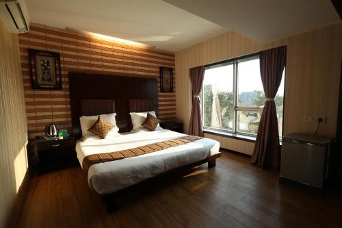 a bedroom with a large bed and a large window at Quaint Suites Hotel & Banquet in Mumbai