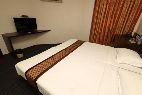 a hotel room with a white bed with a brown blanket at Quaint Suites Hotel & Banquet in Mumbai