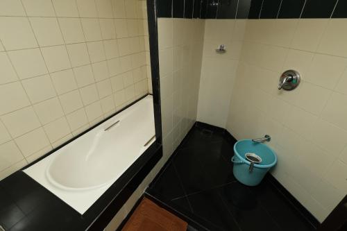 a small bathroom with a tub and a blue bucket at Quaint Suites Hotel & Banquet in Mumbai