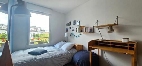 1 dormitorio con cama, escritorio y ventana en Appartement avec terrasse, en Saint-Denis