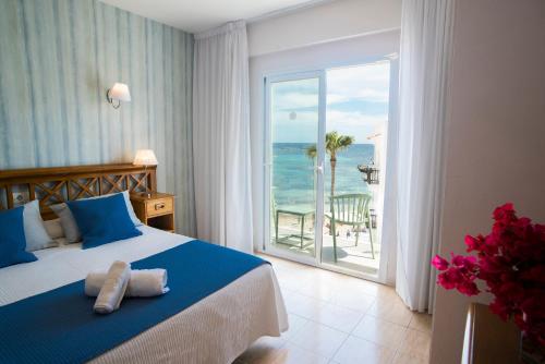 a bedroom with a bed and a view of the ocean at Hostal Mar y Huerta in Es Cana