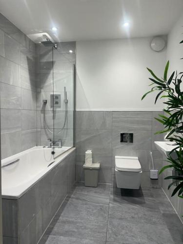 a bathroom with a tub and a toilet and a sink at Relaxing 1 bedroom garden flat. in Brentwood
