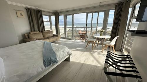 Oceansnest Guest House في بلوبيرجستراند: غرفة نوم مع سرير وغرفة معيشة مع طاولة
