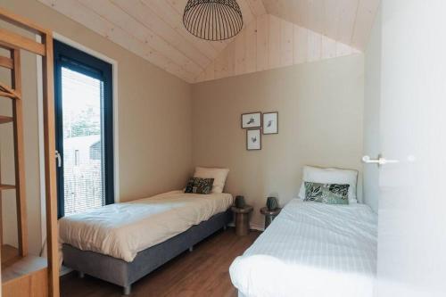 a bedroom with two beds and a window at Knus I Tiny house op de Veluwe in Epe