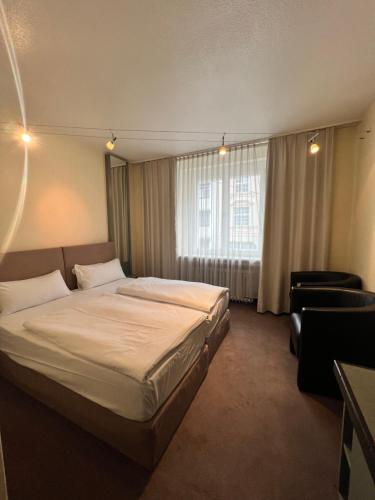 um quarto de hotel com uma cama e uma cadeira em Hotel Monopol City Centre em Dusseldorf
