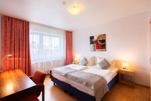 a bedroom with a bed and a desk and a window at Novum Hotel Garden Bremen - Apartments in Bremen