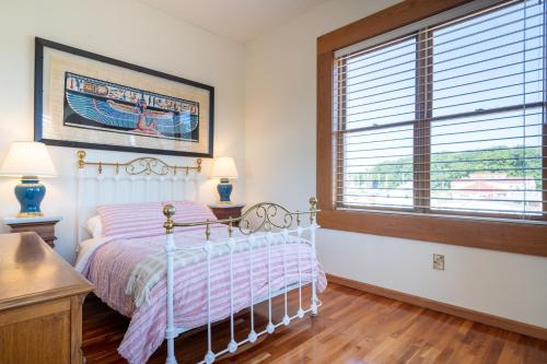 Schlafzimmer mit einem Bett und einem Fenster in der Unterkunft Colonial 1 - studio apartment overlooking the Black River in South Haven