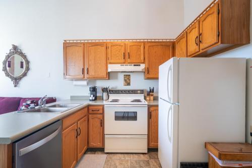 a kitchen with wooden cabinets and a white refrigerator at Colonial 1 - studio apartment overlooking the Black River in South Haven