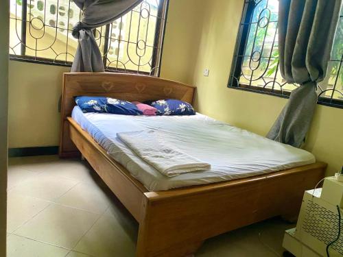Cama pequeña en habitación con 2 ventanas en A private self contained room in a home away from home en Dar es Salaam