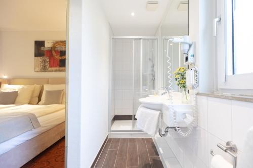a white bathroom with a sink and a bed at Novum Hotel Garden Bremen - Apartments in Bremen