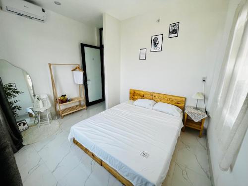 a bedroom with a bed with white sheets and a mirror at Homestay Phủ Cam in Thôn Trường Giang
