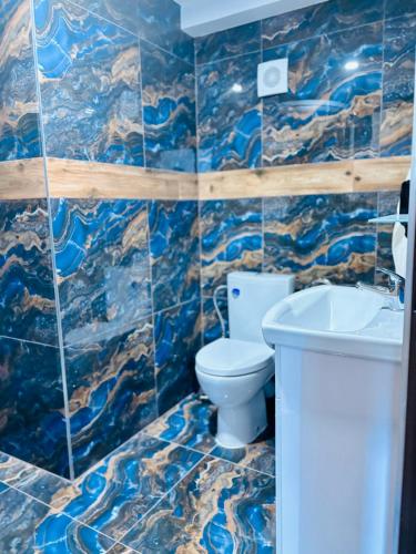 a blue tiled bathroom with a toilet and a sink at Hotel Raj in Dedinky