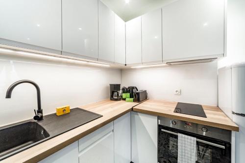 une cuisine avec des armoires blanches et un évier dans l'établissement Le Verlaine AIL, à Villeurbanne