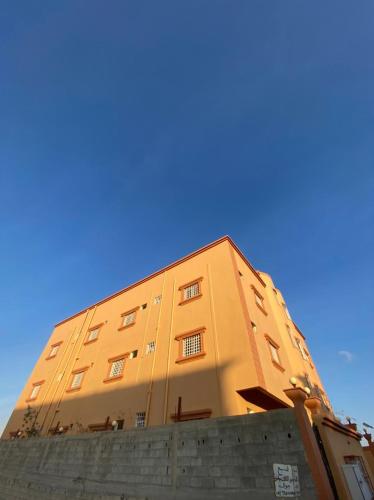 een geel gebouw met een blauwe lucht op de achtergrond bij شقق الزهور in Al Wadeen