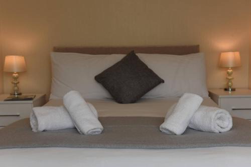 a bed with rolled towels on it with two lamps at Dartside 1 in Dartmouth