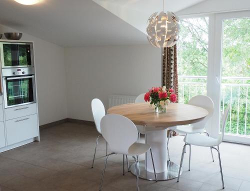 une salle à manger avec une table en bois et des chaises blanches dans l'établissement Urlaub im Alten Apfelgarten - Ferienwohnung Kastanienterrasse, à Sörup