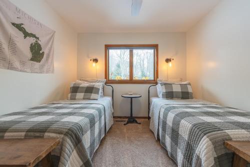Un dormitorio con dos camas y una ventana. en Pure Hygge - 1 block off Lake, Tranquil & Pet Friendly, en Fennville