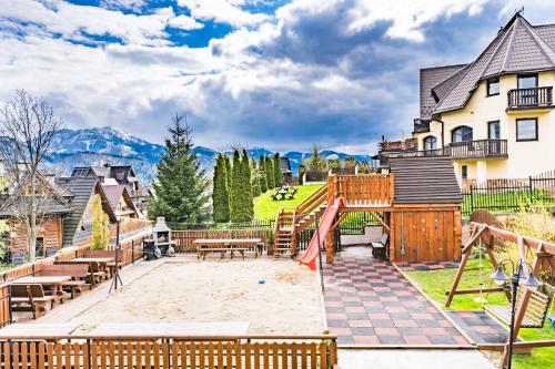a house with a playground with mountains in the background at Górski Pałacyk Kompleks obiektów in Kościelisko