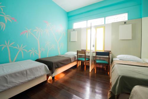 a room with three beds and a table and chairs at 60 Blue House in Chiang Mai