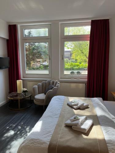 a bedroom with a bed and a chair and two windows at Villa am Januspark in Juist