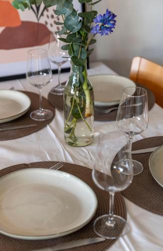 a table with plates and glasses and a vase with flowers at Verblijf bij Bynt in Sneek