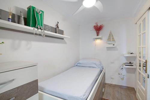 a small white room with a bed and a window at Patalavaca Beach House in Patalavaca