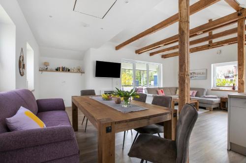 a living room with a wooden table and purple chairs at Ferienhaus Schleibengel in Maasholm