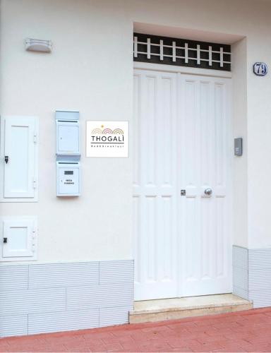 a white building with a door and a sign on it at THOGALì in Santa Ninfa