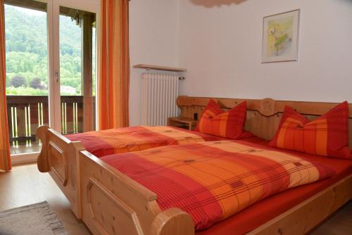 sypialnia z drewnianym łóżkiem z pomarańczowymi i czerwonymi poduszkami w obiekcie Ferienwohnungen Haus Monika w mieście Aschau im Chiemgau