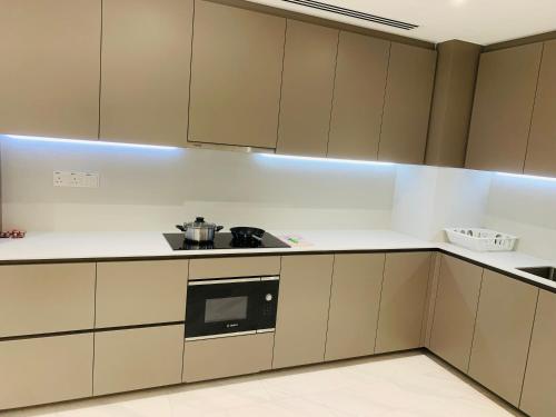 a kitchen with white cabinets and a black microwave at Eaton Residences KLCC by Ikon in Kuala Lumpur