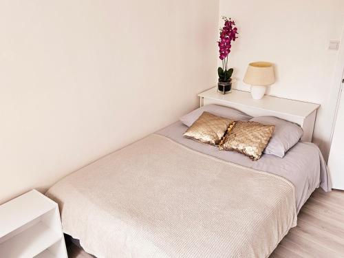 a bedroom with a bed with a lamp and flowers on it at Logement dans résidence - à 10 km du centre ville et à 5 minute du parlement européen avec parking gratuit in Hoenheim