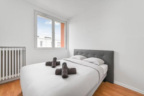 une chambre blanche avec un grand lit blanc avec deux serviettes marron dans l'établissement L'Imprévu - 6pers - Wifi - Paris - Disney, à Vitry-sur-Seine