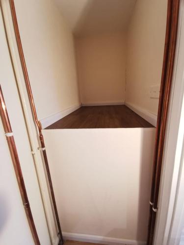 an empty closet with a white door and wooden floor at Private room in a lovely home in Bicester