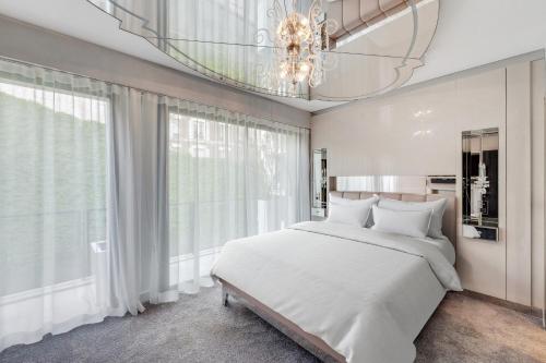 - une chambre avec un grand lit blanc et un lustre dans l'établissement Appartement d'exception - Proche Tour Eiffel, à Paris