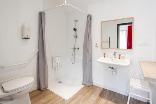 a white bathroom with a toilet and a sink at Hôtel de Matignon Restaurant Le EmLo in Matignon