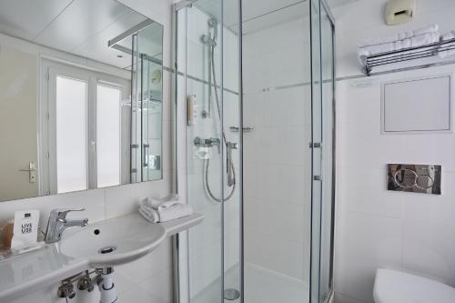 a bathroom with a glass shower and a sink at Hotel Beaugrenelle Tour Eiffel in Paris