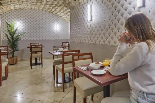 a woman talking on a cell phone in a restaurant at Hotel Beaugrenelle Tour Eiffel in Paris