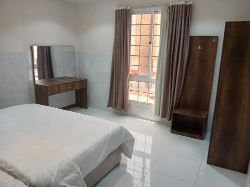 Schlafzimmer mit einem Bett und einem Fenster in der Unterkunft كيان التيسير للشقق المخدومة - Kayan Al Tayseer Serviced Apartments in Quwayzah
