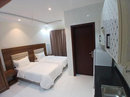 ein Hotelzimmer mit einem Bett und einem Waschbecken in der Unterkunft كيان التيسير للشقق المخدومة - Kayan Al Tayseer Serviced Apartments in Quwayzah