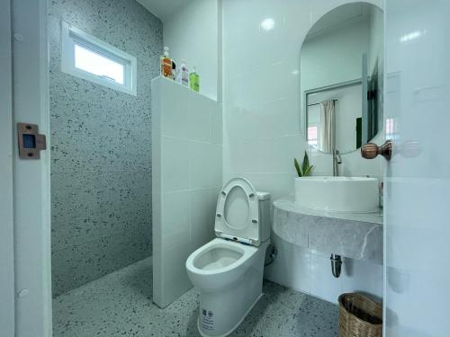 a white bathroom with a toilet and a sink at Vawa Guesthouse in Kanchanaburi