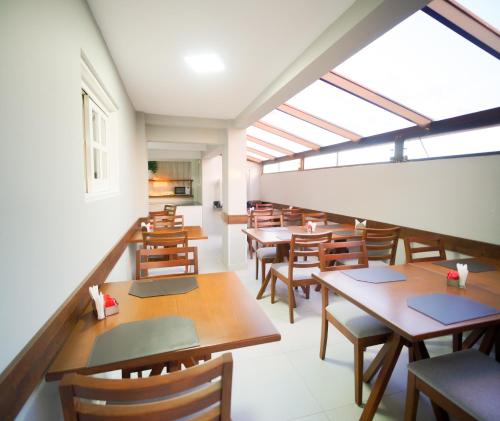 a dining room with wooden tables and chairs at Xangri-La Praia Hotel in Xangri-lá