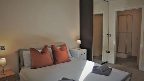 una camera da letto con un letto bianco e cuscini arancioni di Broad Gauge Apartments a Wolverhampton