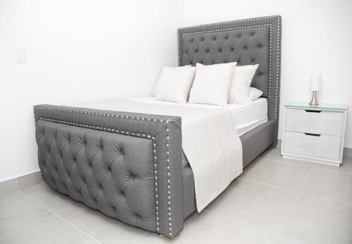 1 dormitorio con cama gris y almohadas blancas en Torre Ginebra, en Medellín