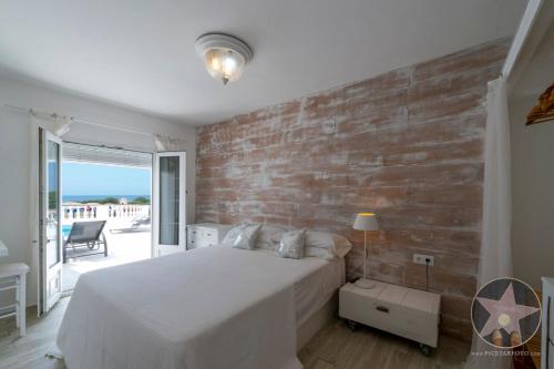 1 dormitorio con cama blanca y pared de ladrillo en VILLA GERMAN 114 sea views en Son Bou